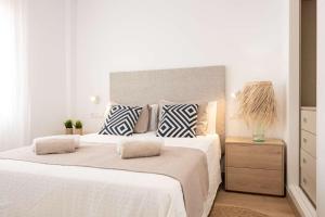 a white bedroom with a large bed with pillows at APARTAMENTOS CARMEN in Maro
