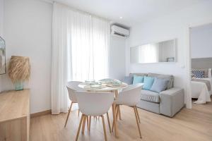 a white living room with a table and chairs at APARTAMENTOS CARMEN in Maro