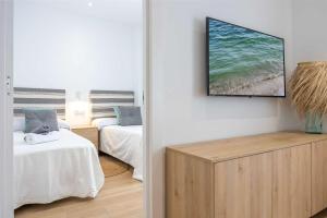 a room with two beds and a tv on the wall at APARTAMENTOS CARMEN in Maro