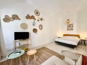 a bedroom with a bed and two tables and a tv at Studio Boho, 4 personnes Nîmes, Lit 160 + CLIM in Nîmes