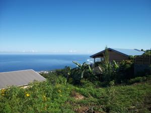 a house on a hill with the ocean in the background at Le Chalet la Fontaine Saint Leu in Saint-Leu