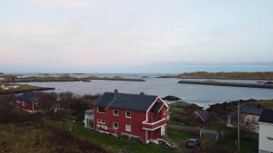 a red house on a hill next to a body of water at Havblikk in Stø