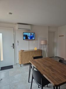 a room with a table and chairs and a tv on the wall at Appartement climatisé avec jardin et piscine in Lecci