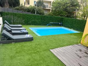 a swimming pool in a yard with green grass at Belle villa familiale 5 Pces Special été in Cannes
