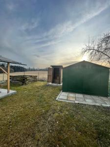 a green building in a field with a fence at Maringotka u potůčku in Černovice