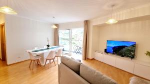 a living room with a couch and a table and a tv at Pestana Green View in Caniço