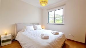 a bedroom with a white bed with a window at Pestana Green View in Caniço