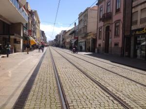 an empty street with train tracks in a city at O Sardinhas in Matosinhos