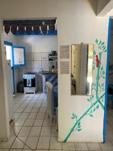 a kitchen with a refrigerator with a tree painted on the wall at Casinha Blue Pipa in Pipa +3 photos