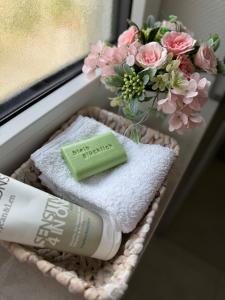 Una canasta con un jabón hidratante y flores junto a una ventana. en Trave Resort Ferienhaus, en Schackendorf