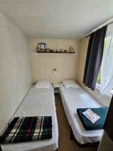 two beds in a small room with a window at Mobile-home hyeres var climatisé dans camping avec piscine jusqu'à 6 personnes in Hyères +7 photos