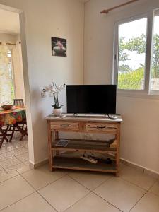 a tv on a wooden stand in a living room at Au Gré des Alizés - Kaz Soley Péyi in Capesterre-de-Marie-Galante