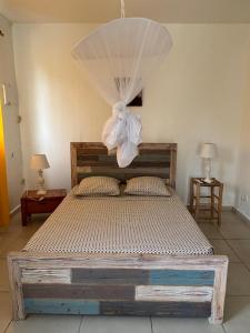 a bedroom with a bed with a chandelier above it at Au Gré des Alizés - Kaz Soley Péyi in Capesterre-de-Marie-Galante