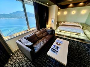 a bedroom with a couch and a bed and a table at Hotel Aligator -Adult Only- in Hatsukaichi
