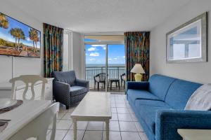 Una sala de estar con un sofá azul y sillas. en Atlantica 601, en Myrtle Beach