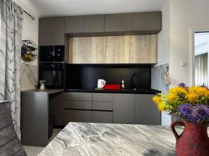 a kitchen with black cabinets and a vase of flowers at Apartman Nonno Božo 2 in Fažana +25 photos