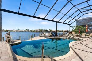 ein Schwimmbecken mit Blick auf das Wasser in der Unterkunft Villa Estelle - Huge lake front Villa in Cape Coral