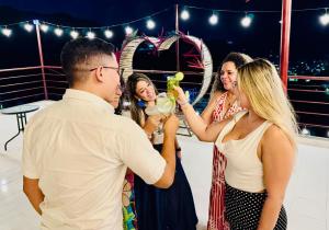 eine Gruppe von Menschen steht um einen Mann herum, der einer Frau etwas zu trinken gibt in der Unterkunft Casa Relax - Adults Only in Taganga + 114 Fotos