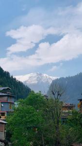 una montagna innevata in lontananza con case e alberi di Hostello Manali a Manāli