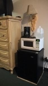 a microwave on top of a refrigerator next to a dresser at Dogwood Motel in Mountain View