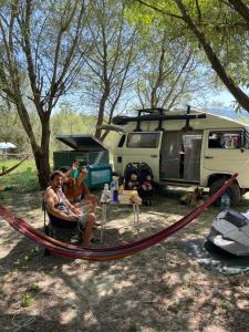 two people sitting in a hammock in front of a camper at Lake Campground Silvano in Berat