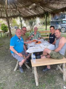 a group of men sitting at a picnic table at Lake Campground Silvano in Berat