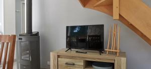 a television sitting on a wooden stand under a staircase at Maison La Petite Boulangerie in Saint-Martin-de-Tallevende
