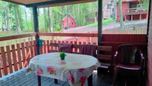 a table and chairs on a porch with a view of a barn at Oleandria-,, Domek Mięta" in Biskupiec
