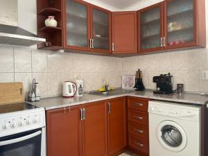 a kitchen with wooden cabinets and a washing machine at Къща за гости НИКА in Kavarna