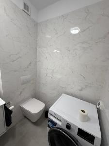 a white bathroom with a toilet and a washing machine at Primavera Pipera Plaza in Voluntari +8 photos