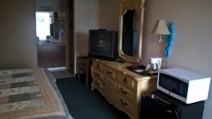 a bedroom with a television and a dresser with a bed at Dogwood Motel in Mountain View