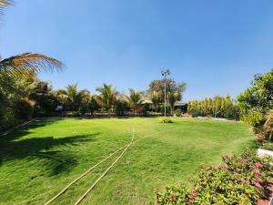 un gran campo de césped con árboles y palmeras en Nandanvan sanskruti farm karjat, en Karjat 8 fotos más
