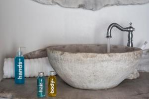 a stone bowl sink with two bottles on a counter at Ydrousa Home, Isternia, Tinos in Istérnia