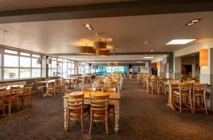 ein Restaurant mit Holztischen und -stühlen und Fenstern in der Unterkunft Sea Bliss Beachfront Caravan, 2 Bed King Ensuite, Sleeps 6, Wrap Decking, Crimdon Dene in Hartlepool