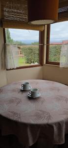 a table with two cups on it with a window at Rincón de los Sueños in Villa General Belgrano