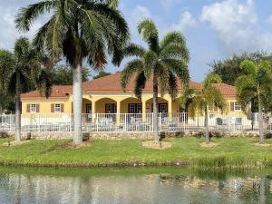 迈尔斯堡A perfect and elegant condo in Fort Myers的一栋黄色房子，周围环绕着棕榈树，前面是一片水域。