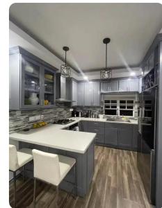 une cuisine avec des placards gris et un comptoir blanc dans l'établissement Cypress Suites, à Goodwill