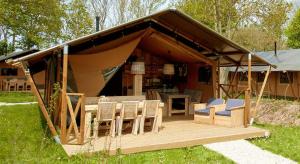 a tent with chairs and a table in a yard at Lodging Le Lac in Lacanau