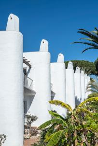 a white fence with palm trees in front of a house at Macdonald Leila Playa Resort in La Cala de Mijas