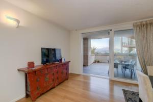 a living room with a tv on a dresser and a sliding glass door at MGH Luxury - Residenza La Perla Peschiera Lakefront in Peschiera del Garda