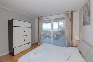 a bedroom with a white bed and a large window at MGH Luxury - Residenza La Perla Peschiera Lakefront in Peschiera del Garda