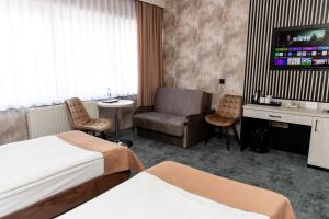 pokój hotelowy z łóżkiem, krzesłem i telewizorem w obiekcie Hotel Aquarius Restaurant Wellness Spa w Ciechocinku