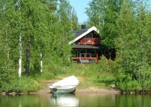 ein Boot im Wasser vor einem Haus in der Unterkunft Loma Rinteelä in Suonenvaara