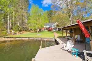 a dock with two chairs and an umbrella on a lake at Herons Watch in Bumpass