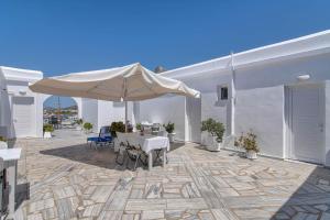 a patio with a table and an umbrella at Akrogiali rooms in Antiparos