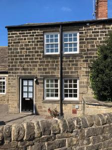 ein Backsteinhaus mit weißen Fenstern und einer Steinmauer in der Unterkunft Railway Cottage Horsforth in Horsforth