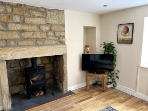 a living room with a stone fireplace and a television at Railway Cottage Horsforth in Horsforth