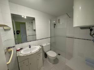 a bathroom with a sink and a toilet and a mirror at Apartamentos GEMA Primera linea Cullera in Cullera
