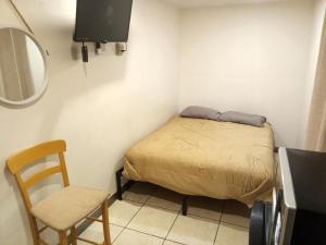 una piccola camera da letto con un letto e una sedia di CampoBella a Phoenix