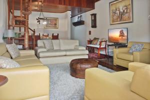 - un salon avec des canapés jaunes et une table dans l'établissement Capivari - Lareira - Estilo Clássico de Casa de Campo, à Campos do Jordão